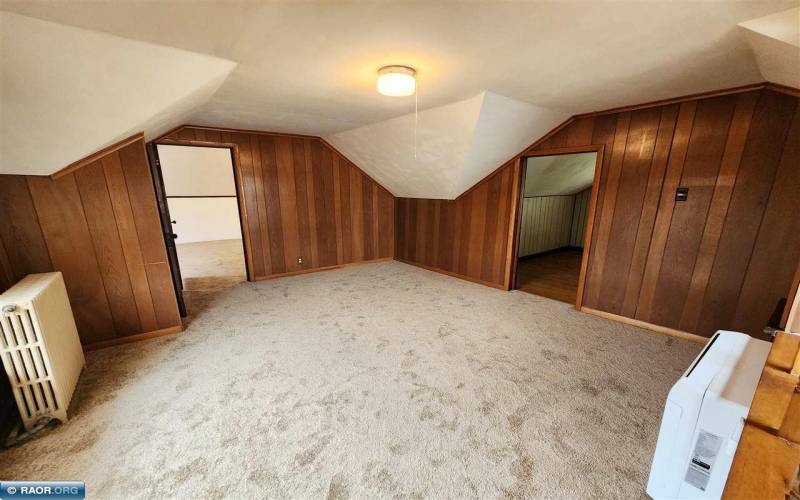 Additional upper-level living space featuring lofted ceiling, wood paneling, heat/cool mini split