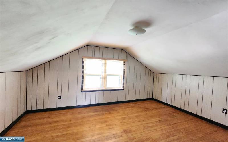 Upper-level bedroom with hardwood floors and commercial blinds