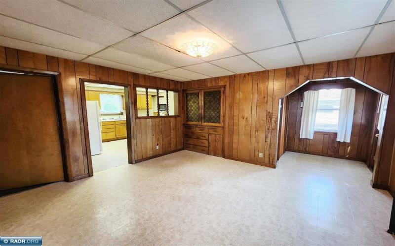 Main floor dining room with a convenient kitchen pass-through, wood paneling, a drop ceiling.