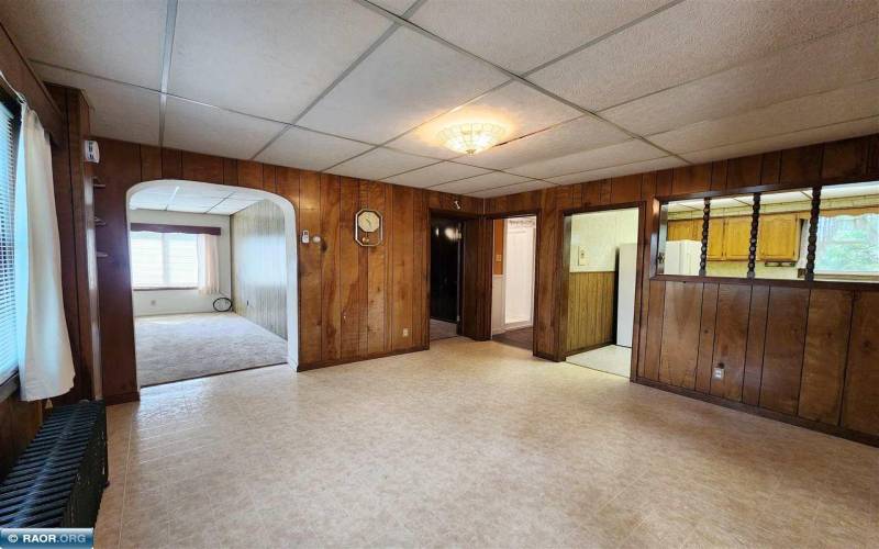 Main floor dining room with a convenient kitchen pass-through, wood paneling, a drop ceiling.